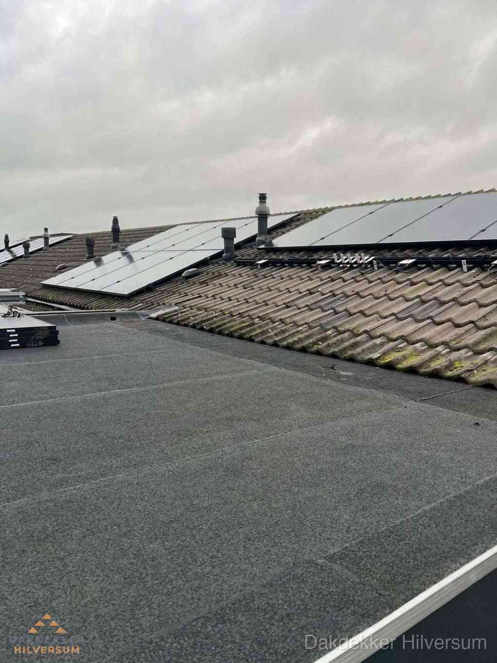 Plat dak inspectie met bitumen bedekking naast schuin pannendak in Hilversum
