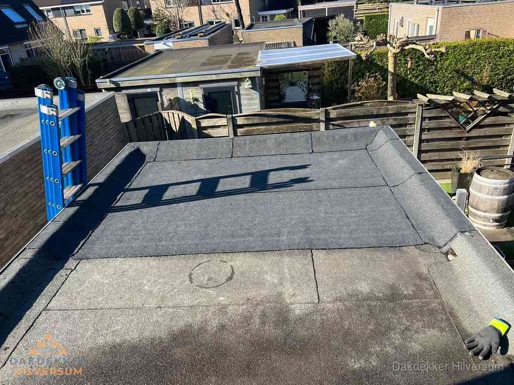 Dakdekker legt onderlaag op plat dak met houten constructie in Hilversum