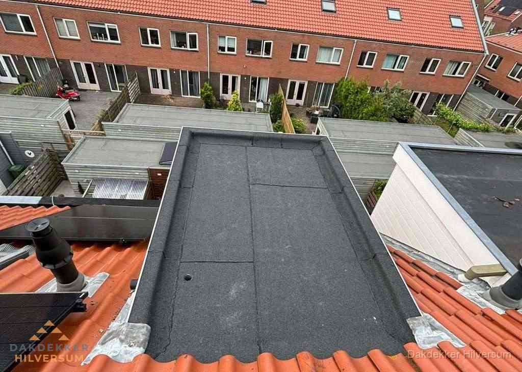 Plat dak met bitumen bedekking naast dakkapel in Hilversum