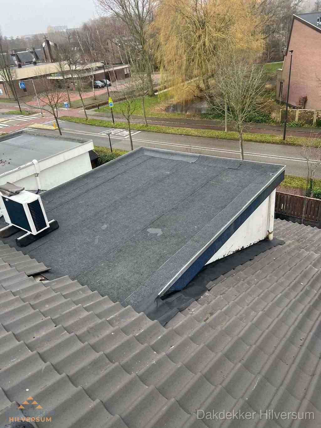 Plat dak met bitumen dakbedekking naast schuin pannendak in Hilversum